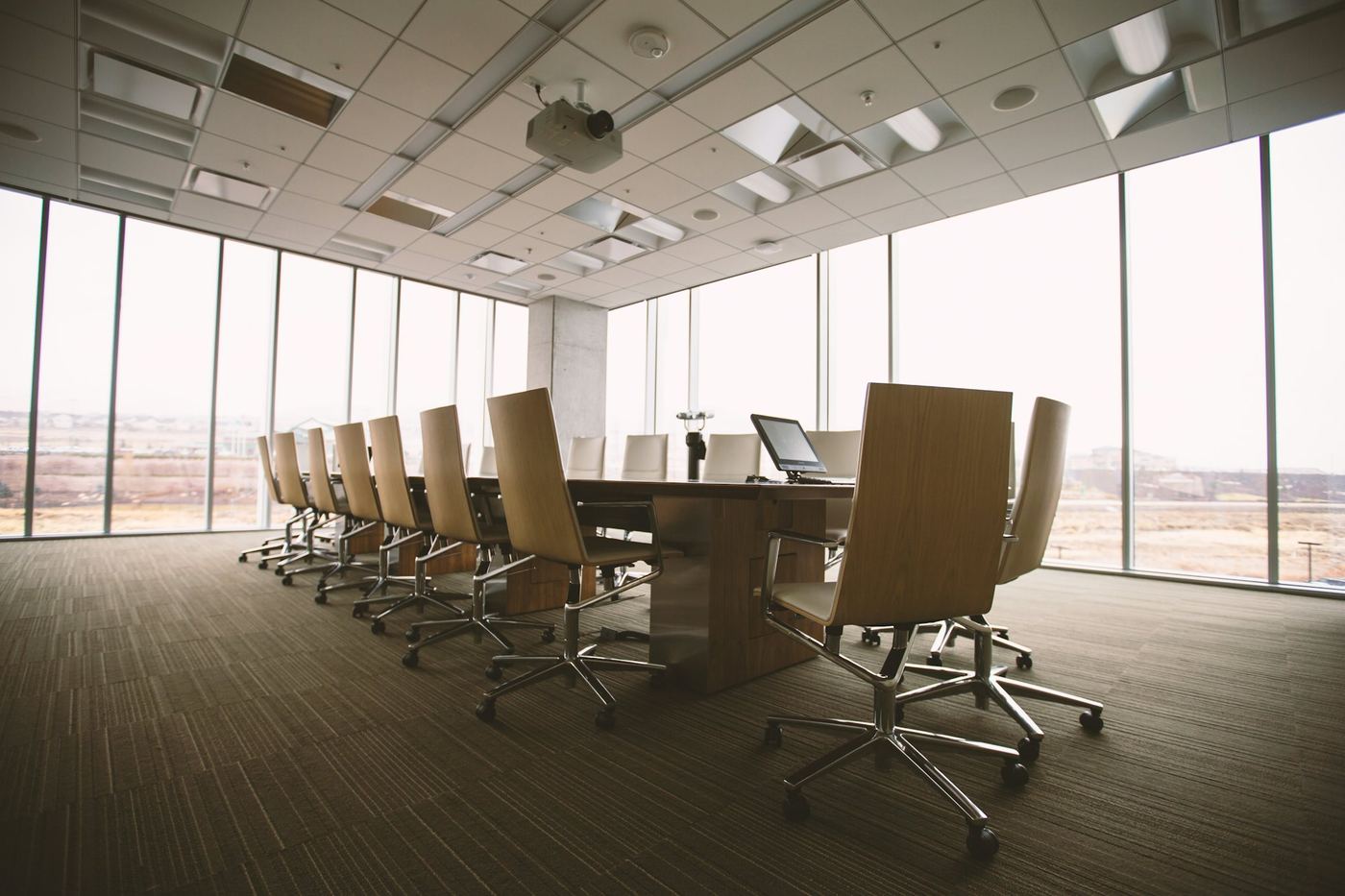 A classic boardroom with a long table and leather chairs lit by a window wall